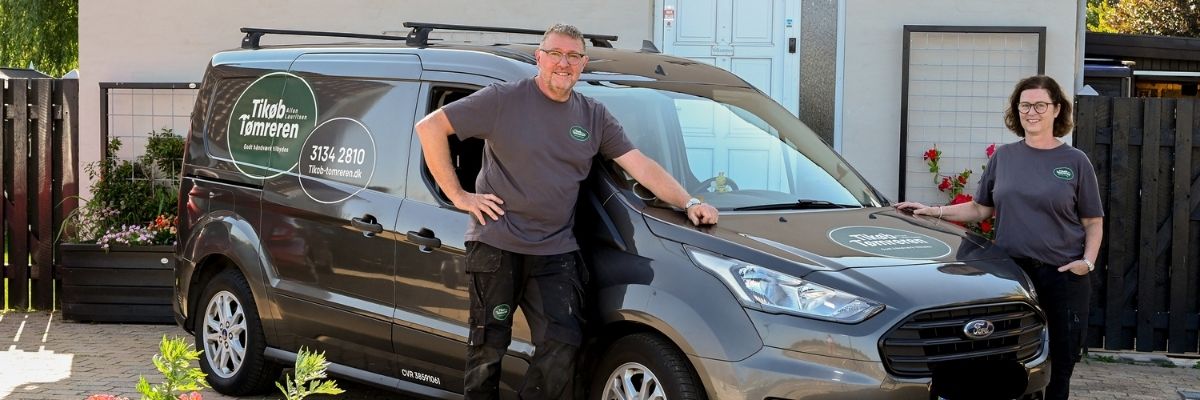 Tikøb Tømreren står foran sin firmabil sammen med tømrerfruen